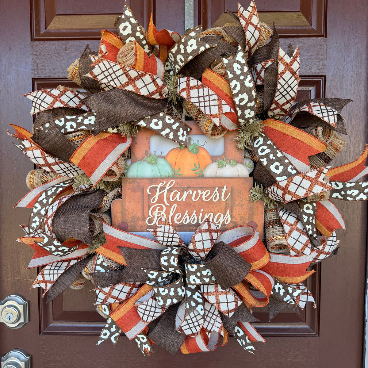 Harvest Blessings wreath. Rich pumpkin orange, deep brown, cream, and soft green come together in a full, layered design that feels cozy, cheerful, and perfect for the season.