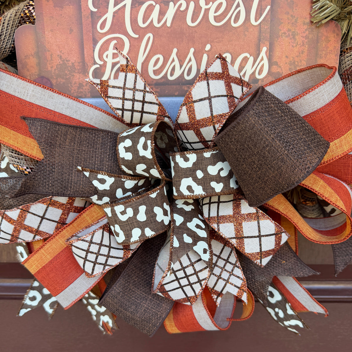 Harvest Blessings wreath. Rich pumpkin orange, deep brown, cream, and soft green come together in a full, layered design that feels cozy, cheerful, and perfect for the season.