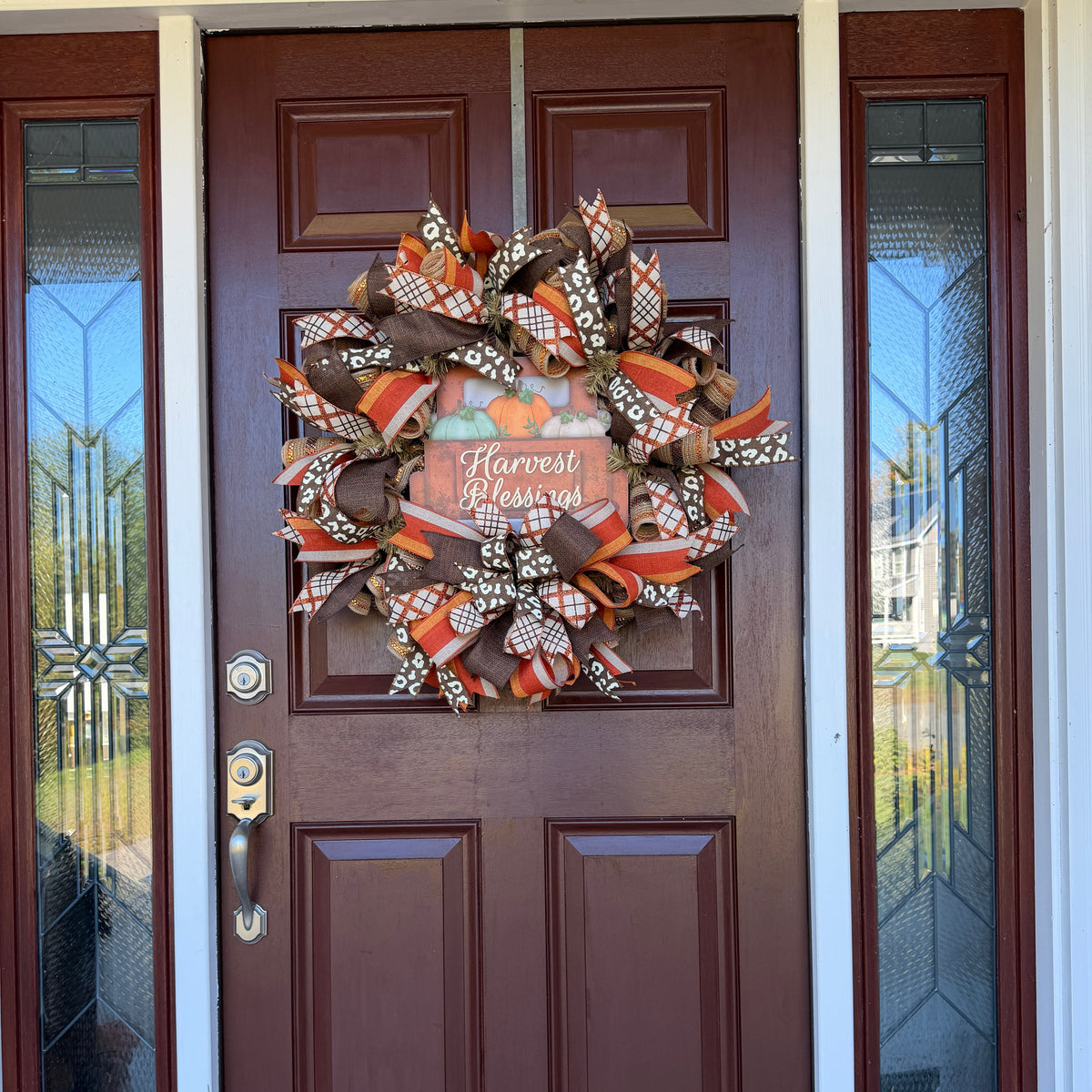 Harvest Blessings wreath. Rich pumpkin orange, deep brown, cream, and soft green come together in a full, layered design that feels cozy, cheerful, and perfect for the season.