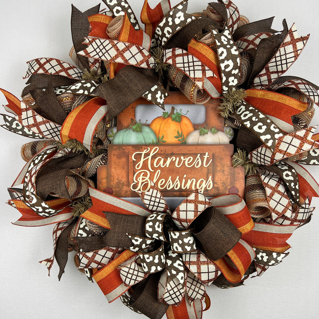 Harvest Blessings wreath. Rich pumpkin orange, deep brown, cream, and soft green come together in a full, layered design that feels cozy, cheerful, and perfect for the season.