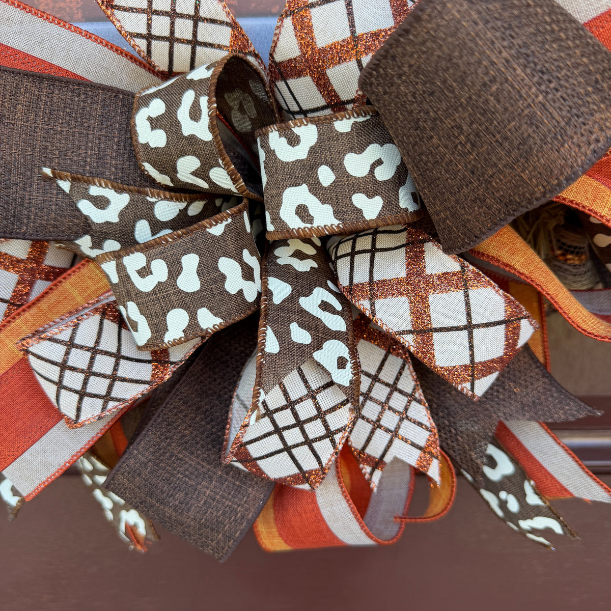 Harvest Blessings wreath. Rich pumpkin orange, deep brown, cream, and soft green come together in a full, layered design that feels cozy, cheerful, and perfect for the season.