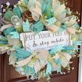 Handmade coastal welcome wreath with aqua blue, cream, and beige ribbons, floral accents, and a farmhouse-style welcome sign for beach house or summer front door decor.