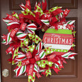 Handmade red and lime green Christmas deco mesh wreath with striped ribbons, No Peeking accents, and Merry Christmas sign.