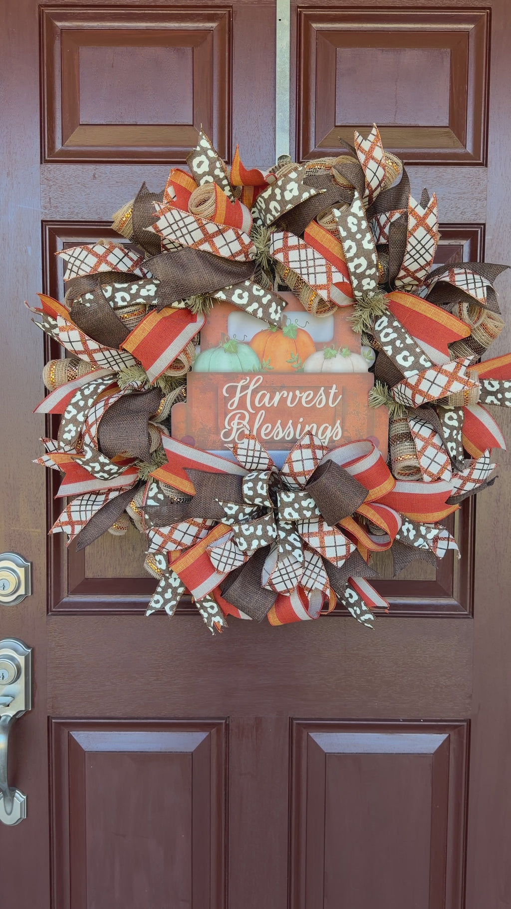 Harvest Blessings wreath. Rich pumpkin orange, deep brown, cream, and soft green come together in a full, layered design that feels cozy, cheerful, and perfect for the season.