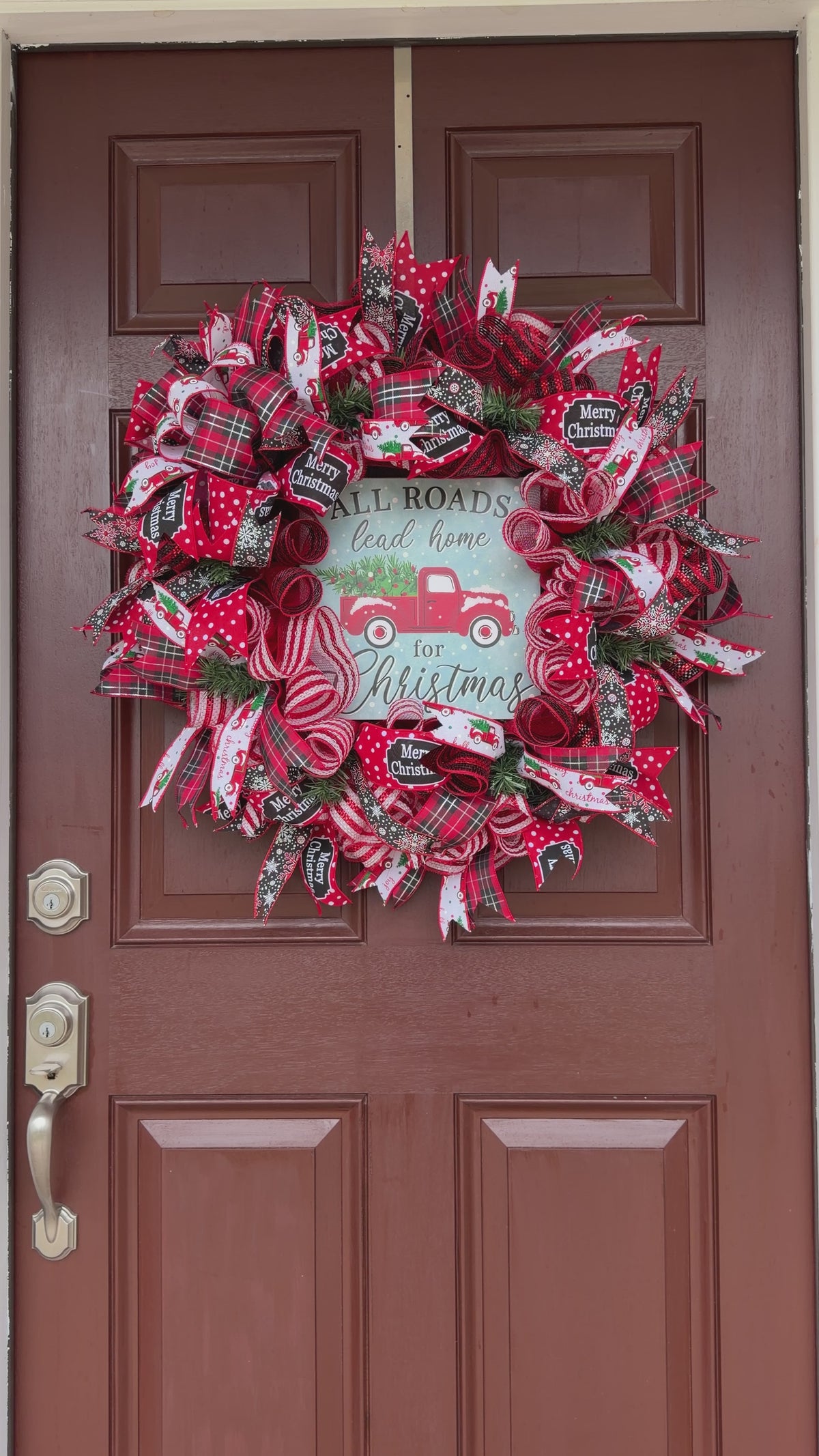 Handmade red truck Christmas deco mesh wreath with red and black plaid ribbons, snowflake accents, and All Roads Lead Home for Christmas sign.