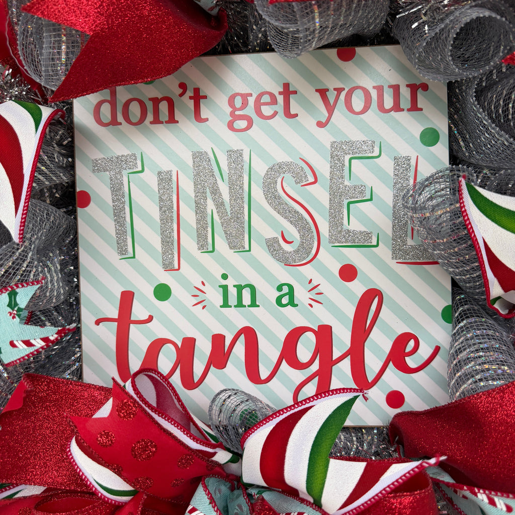 Handmade Christmas deco mesh wreath with silver mesh, red glitter ribbons, candy cane accents, and Don't Get Your Tinsel in a Tangle sign.