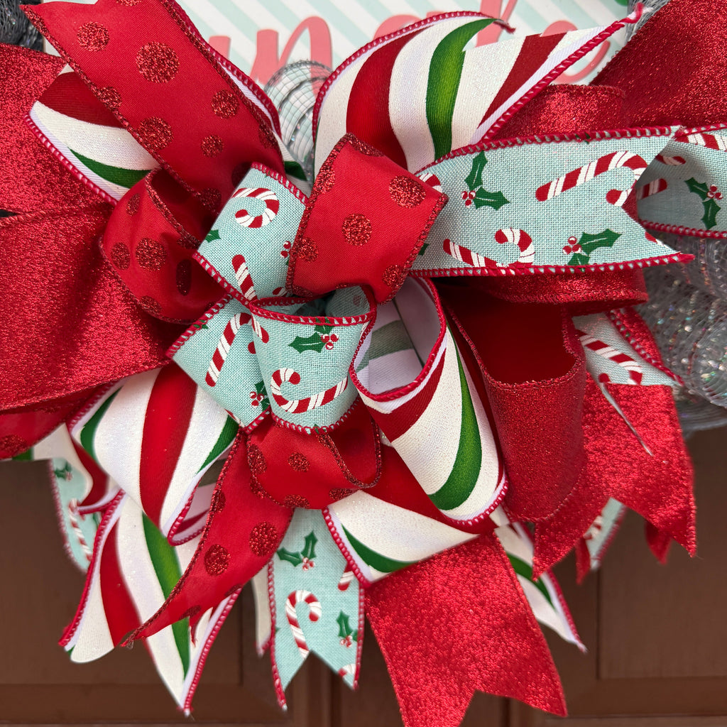 Handmade Christmas deco mesh wreath with silver mesh, red glitter ribbons, candy cane accents, and Don't Get Your Tinsel in a Tangle sign.