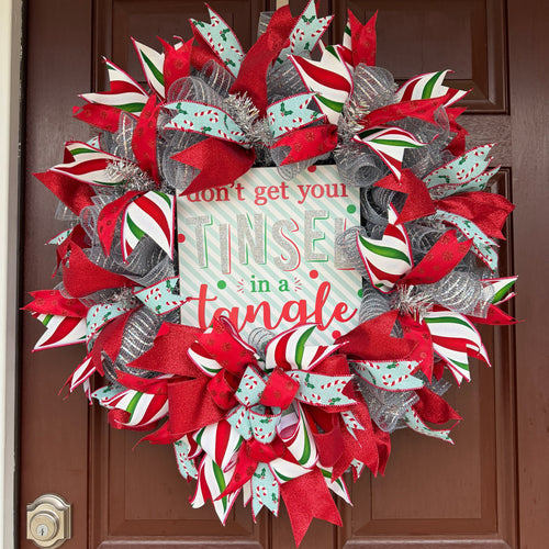 Handmade Christmas deco mesh wreath with silver mesh, red glitter ribbons, candy cane accents, and Don't Get Your Tinsel in a Tangle sign.