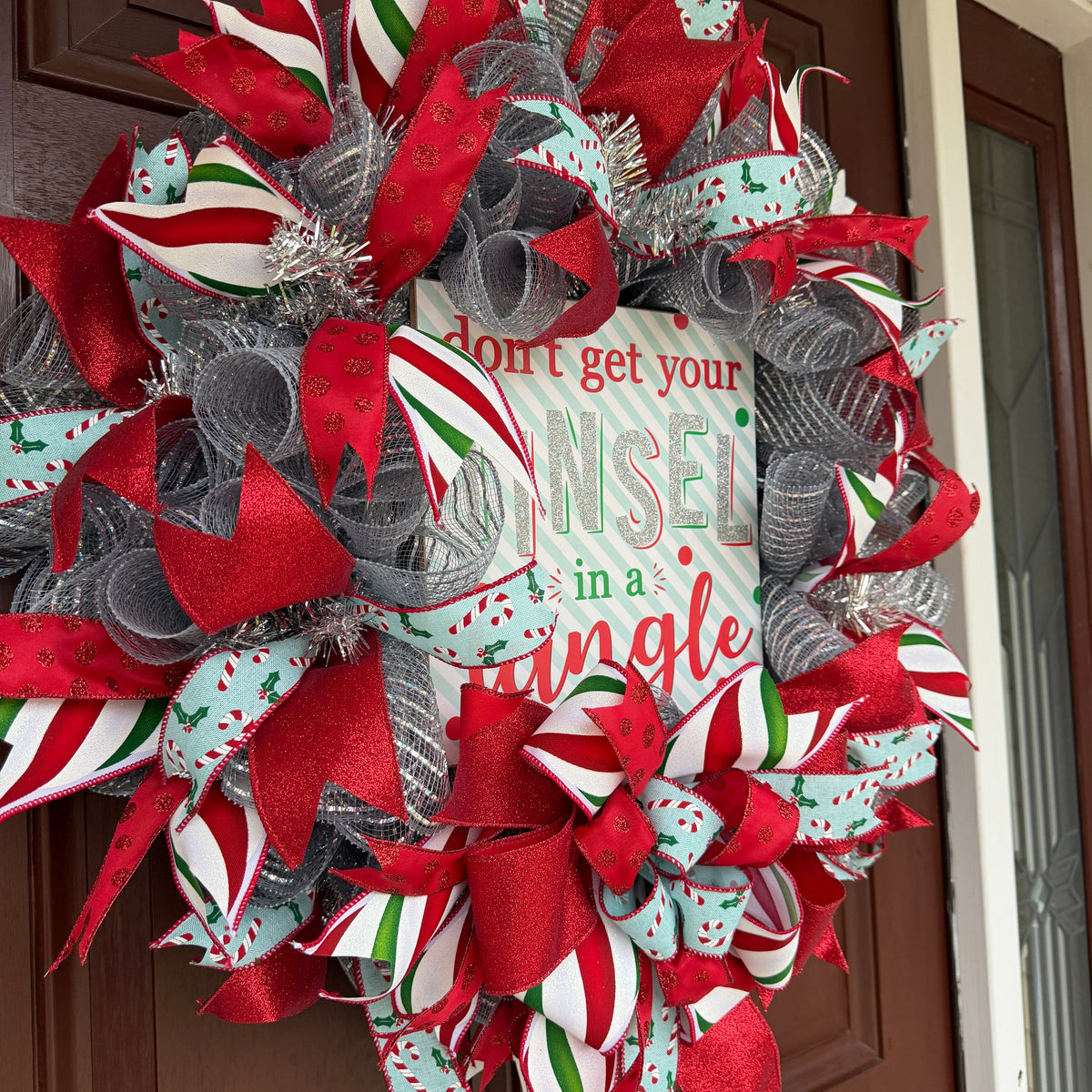 Handmade Christmas deco mesh wreath with silver mesh, red glitter ribbons, candy cane accents, and Don't Get Your Tinsel in a Tangle sign.