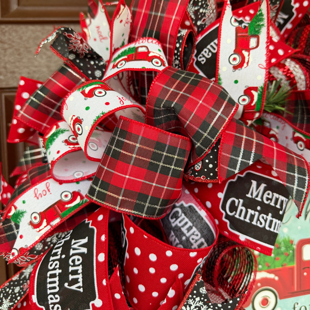 Handmade red truck Christmas deco mesh wreath with red and black plaid ribbons, snowflake accents, and All Roads Lead Home for Christmas sign.